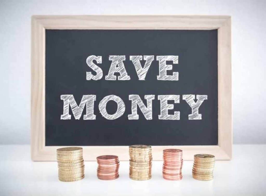 Save money as a teenager written on black chalkboard with coins in front of it