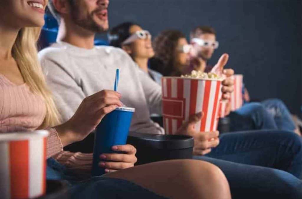 teenagers at movie theatre with 3d glasses and popcorn