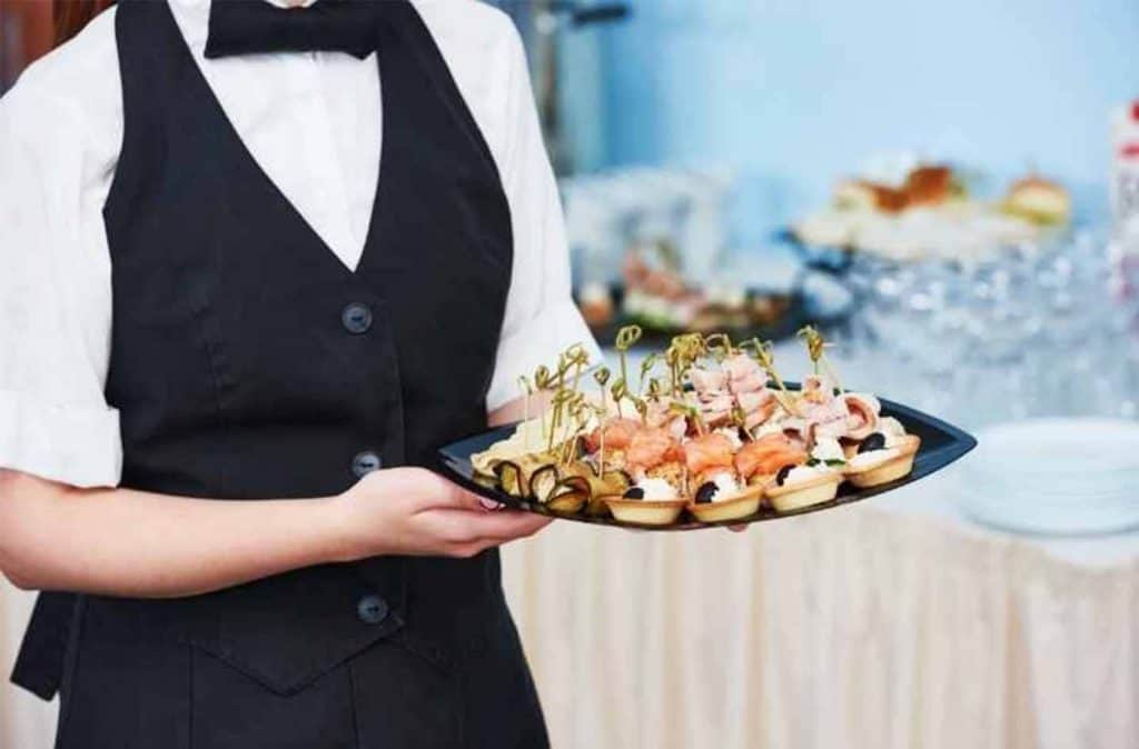 young woman working catering job carrying tray with food appetizers