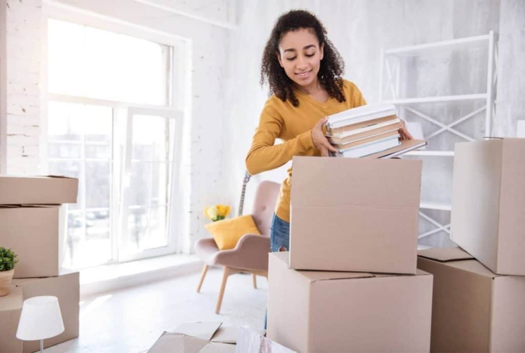 girl moving out of parents house, packing boxes with books