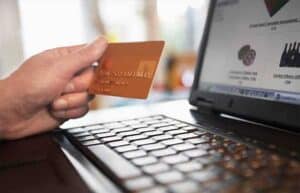 What to know before applying for a credit card. Credit card being held by a person in front of laptop computer