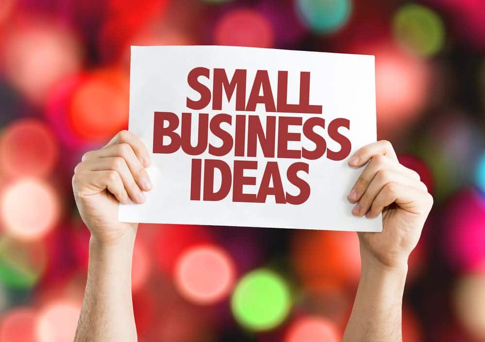 Two hands holding white sign with red letters that says small business ideas with circles in the background