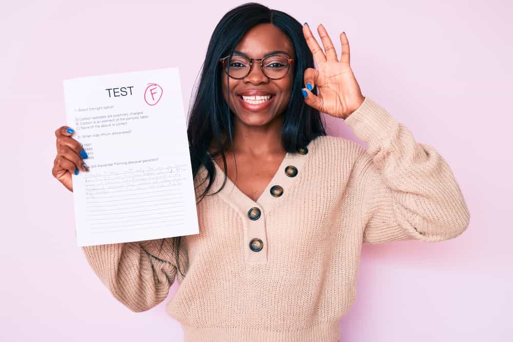 Young african american woman showing a failed exam doing ok sign with fingers