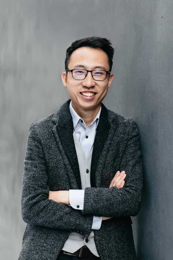 Jacky Kuk, young asian financial planner in sweater leaning on wall
