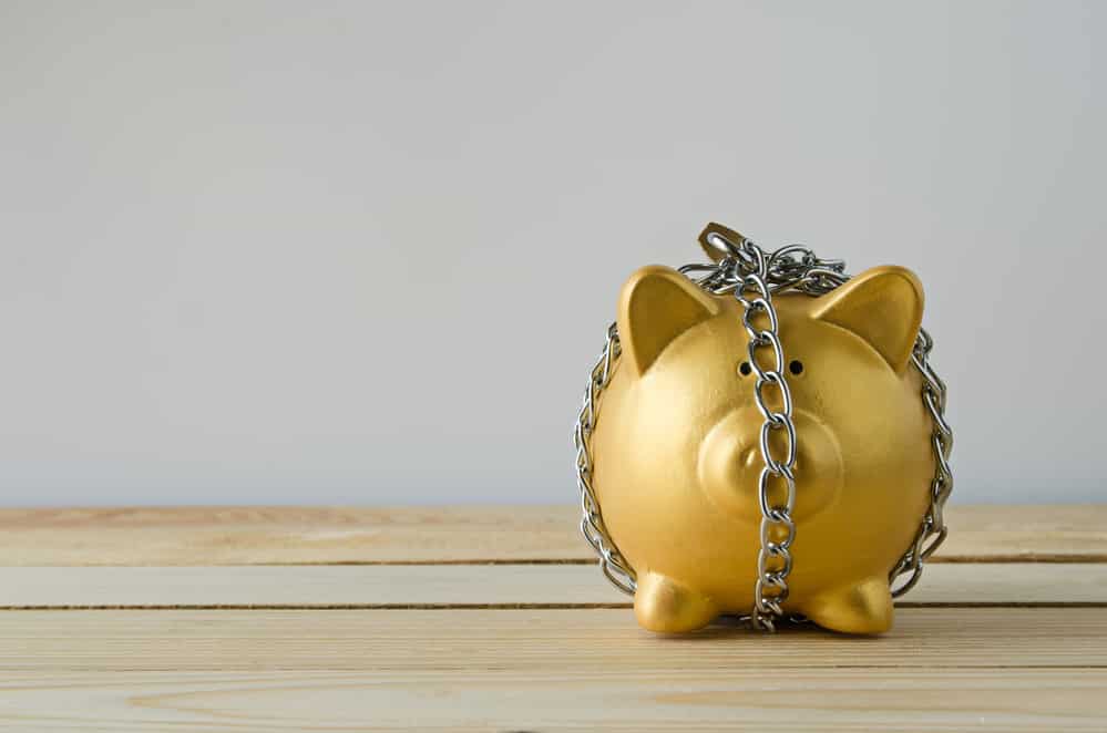 Yellow piggy bank with chain around it to not spend money from money saving plan