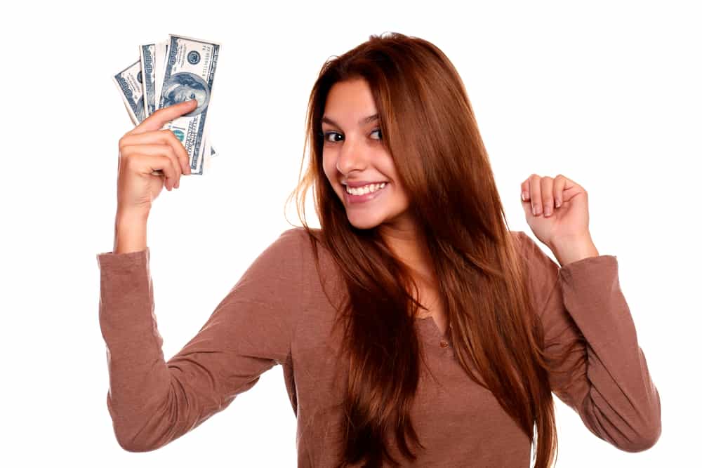 young woman with brown hair and brown shirt showing the cash money she saved in her hand