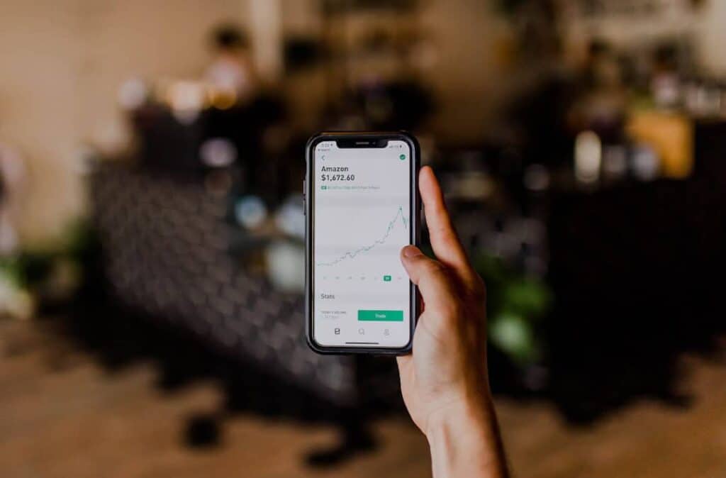 Person holding smartphone showing Amazon stock growth chart.