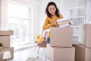 How much you should save before moving out, girl packing boxes of books