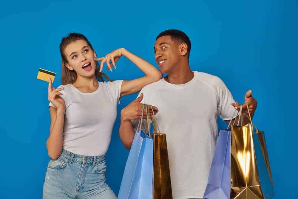 Teenagers enjoying shopping with credit cards and shopping bags.