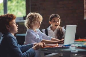three kids happy sitting at a laptop computer