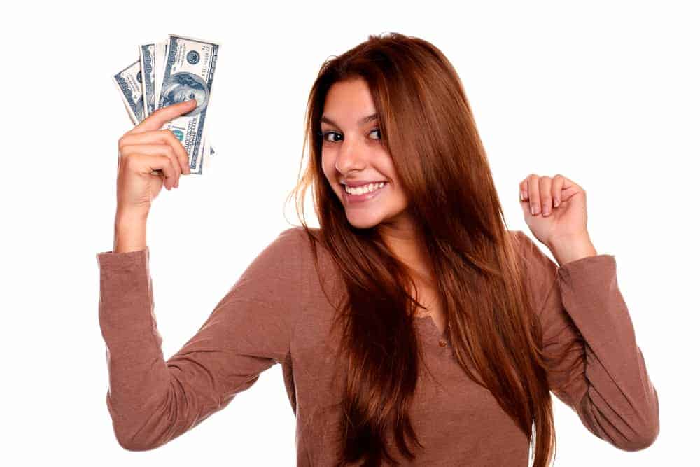 Teen girl holding cash, promoting saving money as a teenager without a job.