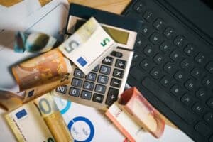 Calculator, euro and dollar bills, and a laptop for financial management.