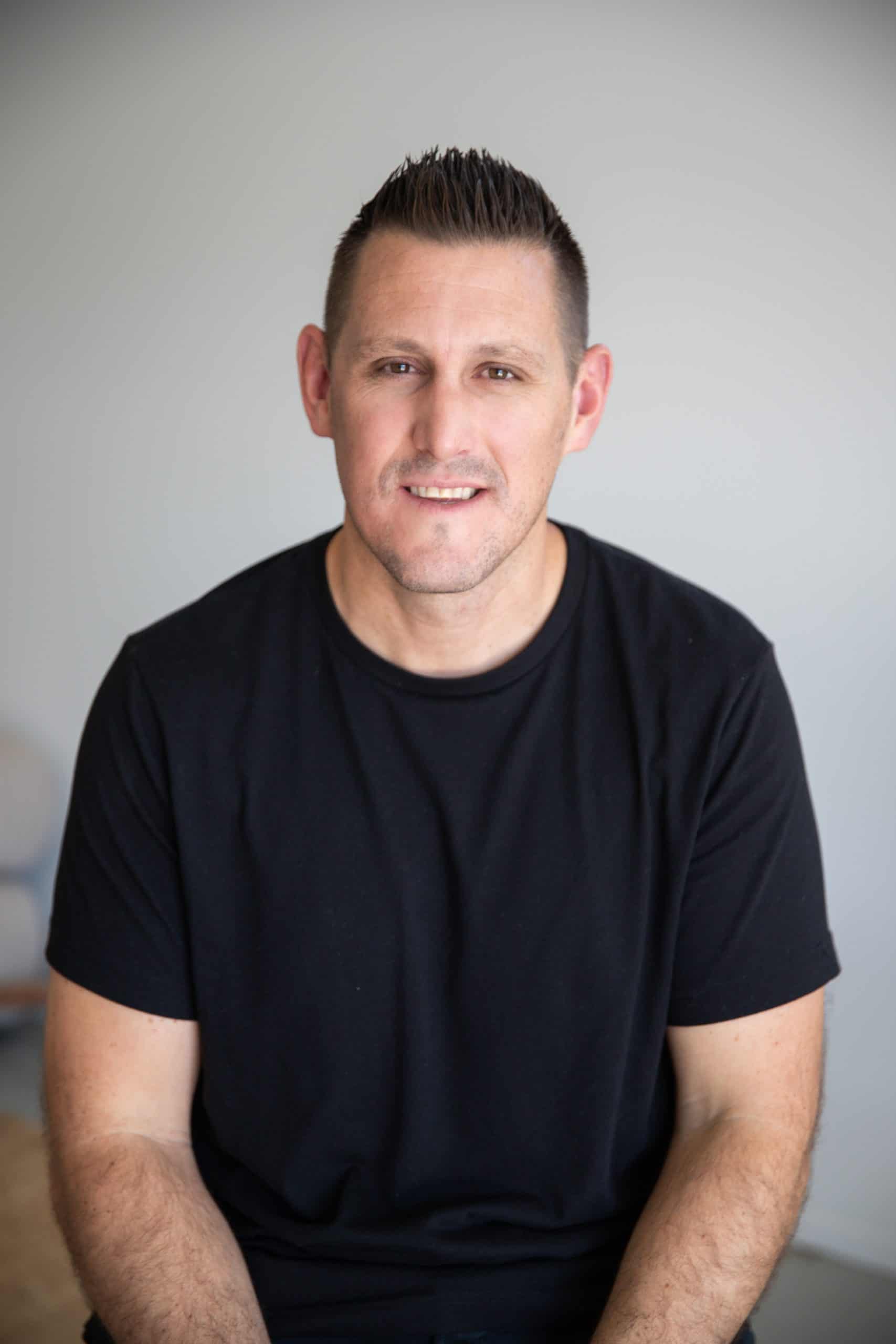 Robert Puharich sitting wearing a black t shirt headshot