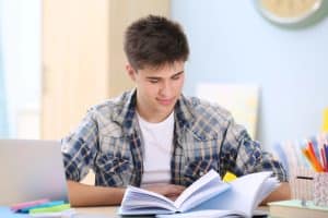 Teenager studying at home with an open book, representing the AI prompts for school guide