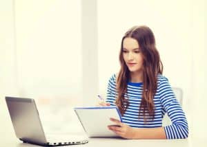 Teenage girl reviewing her college application notes with a laptop, representing the AI prompts for college applications guide