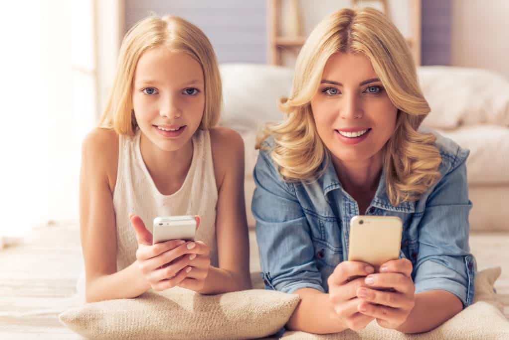 Parents guide to teens and AI: mother and teenage daughter smiling while looking at their phones together